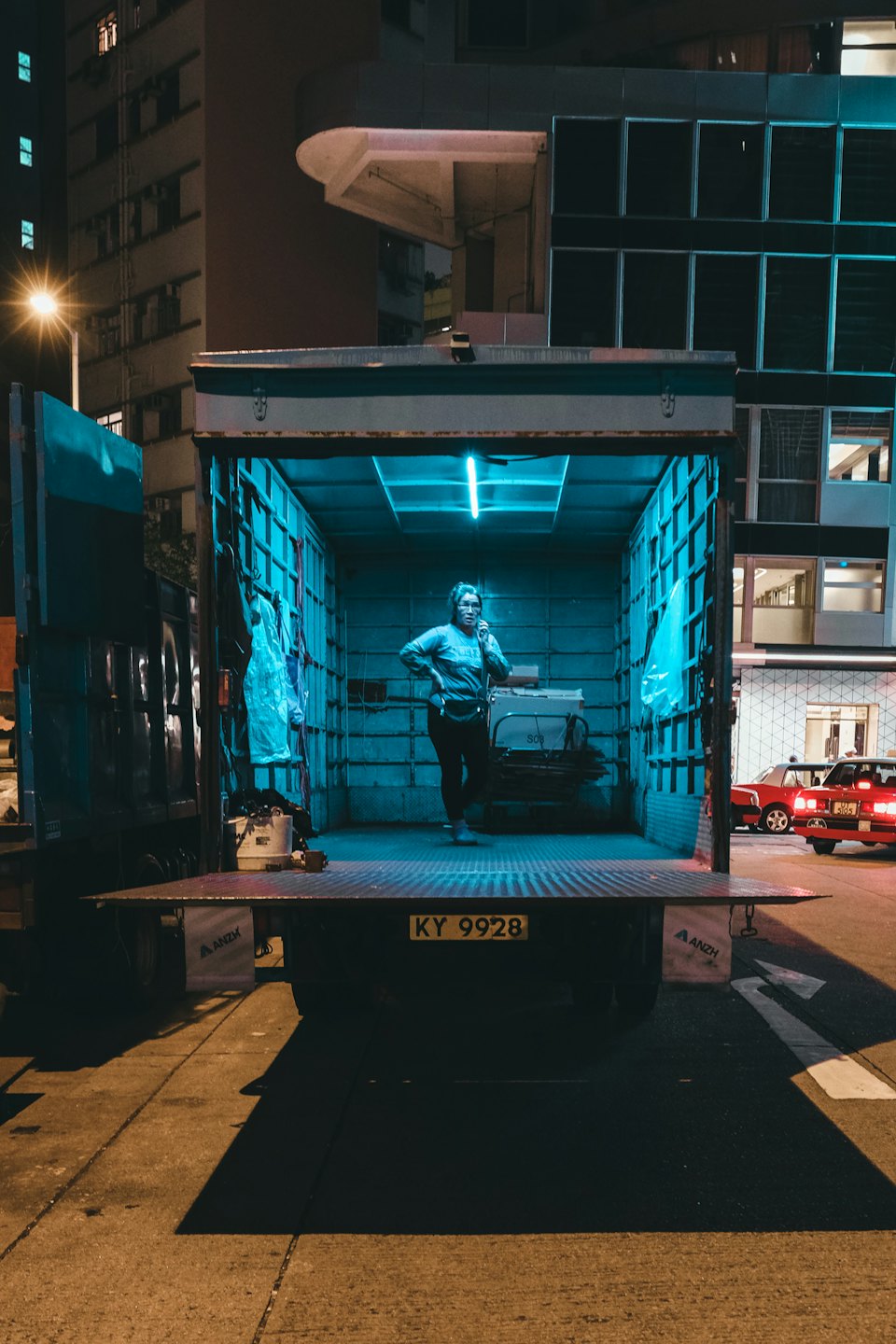 Donna in piedi su un camioncino a pianale in una strada urbana.