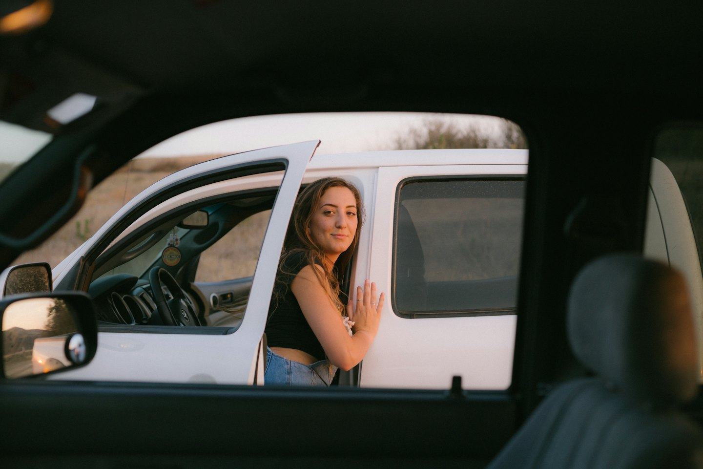 Donna sorride appoggiata alla portiera di un pick-up bianco.
